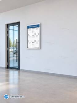 Gablota P405Lx9 z kartkami A4 na białej ścianie salonu samochodowego, obok szklanych drzwi wejściowych
