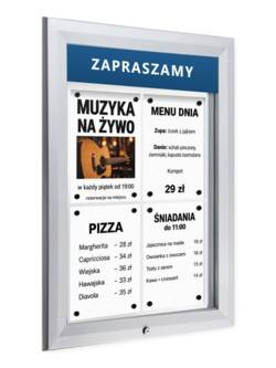Srebrna gablota zewnętrzna P405Lx4 z czterema kartkami A4 za szkłem i przykładowym napisem ZAPRASZAMY na tabliczce u góry, widok pod kątem
